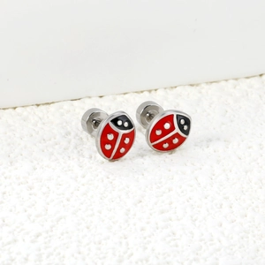 Détail macro de boucles d'oreilles coccinelle rouge en acier inoxydable plaqué or 18 carats