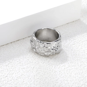 Nahaufnahme eines breiten Edelstahlrings mit Hammerschlag-Textur und Stern-Perle