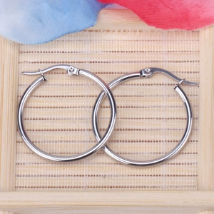 Macro view of 2mm silver stainless steel hoop earrings with secure clasp on a mat