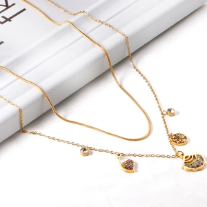 Dettaglio di una collana dorata a strati stile oceano con pendenti a conchiglia e disco