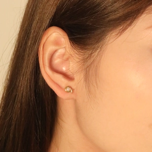 Close-up of elegant gold cross earrings with pearl on a female model ear lobe