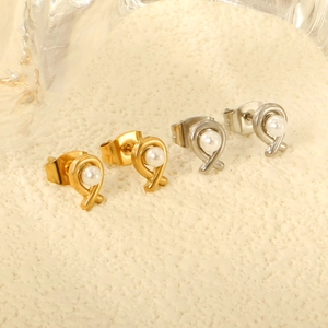 Crossed knot pearl stud earrings set in gold and silver finish on textured background