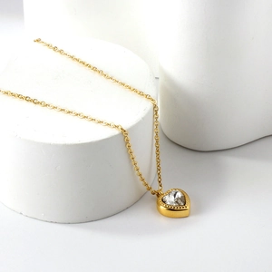 Gold heart pendant necklace with large clear cubic zirconia stone on a white display