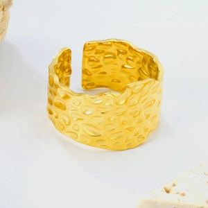 Détail d'une bague large dorée avec texture martelée irrégulière et ouverture ajustable
