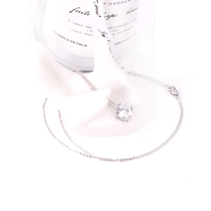 Detailed shot of silver-colored chain necklace with round zircon on white hand stand