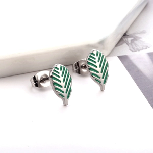 Macro view of leaf-shaped silver earrings with green enamel and butterfly back closure