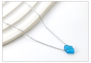 Detail of silver Hamsa hand pendant with vibrant blue crushed opal texture on chain