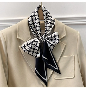 Close-up of houndstooth pattern silk scarf tied on a beige blazer lapel for styling