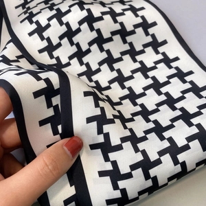 Detailed view of black and white geometric silk scarf texture with premium stitching