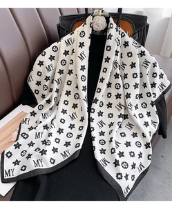 Détail d'un foulard en soie au motif monogramme noir et blanc drapé sur un vêtement noir