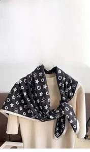 Détail d'un foulard en soie noir et blanc porté sur un pull à col roulé beige