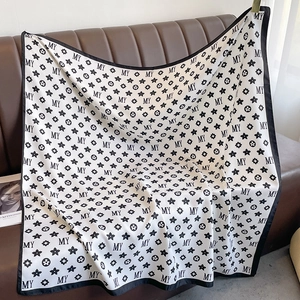 Détail d'un foulard carré en soie noir et blanc avec monogramme MY et motifs d'étoiles