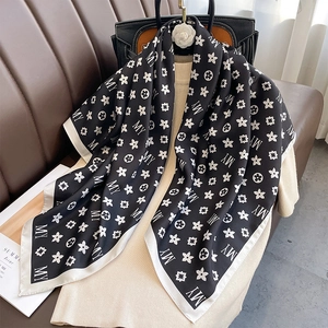 Détail d'un foulard en soie noir et blanc à motif MY noué sur un sac à main avec élégance