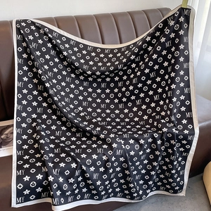 Détail d'un élégant foulard en soie noir et blanc avec motifs floraux et lettres MY