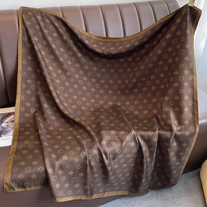Détail d'un foulard en satin marron à motifs monogrammes sur canapé en cuir