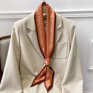 Detail eines Seidenschals mit Paisley-Muster an einem cremeweißen Blazer