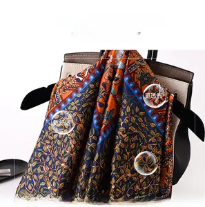Silky satin scarf featuring vibrant tree patterns and geometric borders draped on a bag