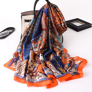 Artistic silk scarf with vintage bird and flower prints draped over a classic handbag