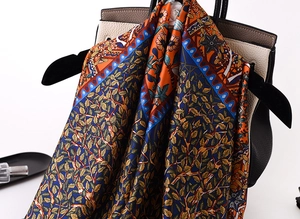 Detail of luxury silk scarf with floral pattern draped on a classic leather handbag