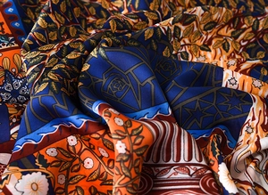 Close-up of silk-feel scarf with vintage floral and geometric patterns in deep blue and orange