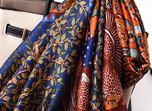 Close-up of silk satin scarf with artistic orange and blue print on leather bag