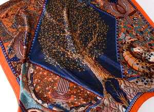 Detailed view of luxury silk scarf featuring artistic tree of life and vibrant navy orange patterns