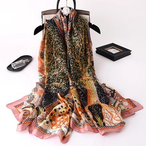 Artistic printed silk scarf with floral patterns displayed with luxury fashion accessories