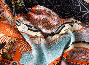 Detailed close-up of vibrant floral printed silk scarf with smooth satin texture