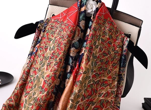 Detail of red silk scarf with Tree of Life print draped over a luxury leather handbag