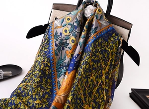 Detail of silk satin scarf with floral and bee prints draped on a luxury leather bag