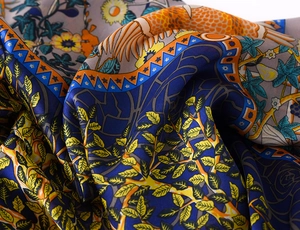 Detailed close-up of premium silk scarf featuring vibrant botanical and bird feather prints