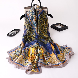 Elegant floral silk satin scarf in blue and orange draped over a luxury handbag