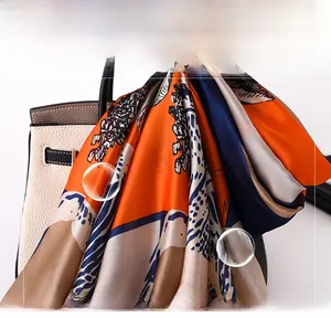 Detail of printed silk scarf with orange and blue abstract patterns on a handbag
