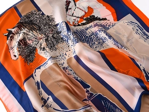 Close-up of luxury silk-like scarf with vibrant orange horse pattern and satin finish