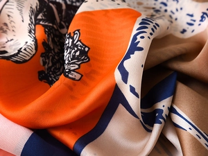 Detailed macro view of vibrant horse print silk scarf fabric with premium soft texture