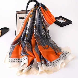 Detail of printed silk scarf with geometric patterns tied to a beige handbag handle