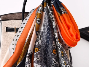 Detailed close-up of colorful silk scarf tied on a luxury leather handbag handle
