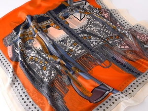 Detailed macro view of equestrian saddle pattern on a vibrant orange silk-like scarf