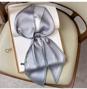 Macro shot of grey-blue silk scarf with houndstooth edges and a pearl ring accessory