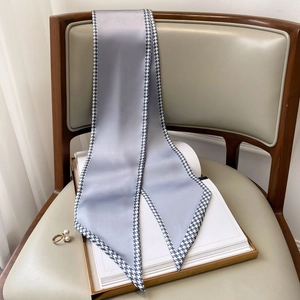 Close-up of grey-blue silk twilly scarf with houndstooth edge draped on a vintage chair