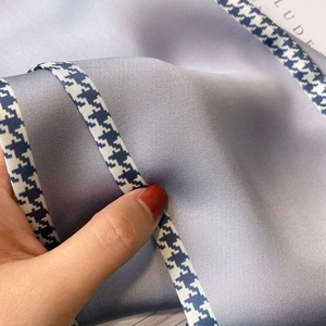 Detailed macro view of soft lavender silk scarf with navy houndstooth trim and satin sheen
