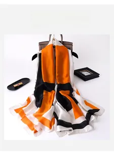 Detail of silk-like scarf with orange and black geometric blocks on a handbag