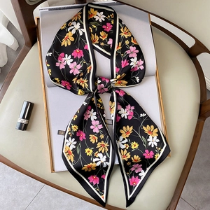 Pañuelo estrecho de seda con estampado floral atado con lazo sobre una revista de moda