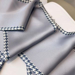 Detail of grey silk scarf with houndstooth trim showing smooth texture and luster