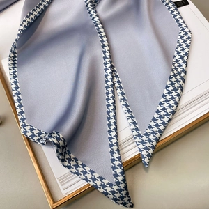 Detail of light blue silk scarf showing hounds-tooth pattern and smooth satin texture