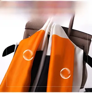 Detail of soft silk-like scarf with orange and ivory geometric pattern on a handbag