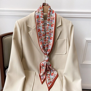 Primer plano de un pañuelo de seda floral anudado en un blazer beige colgado en percha