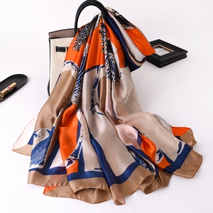 Elegant silk scarf with orange and blue print draped over a stylish handbag