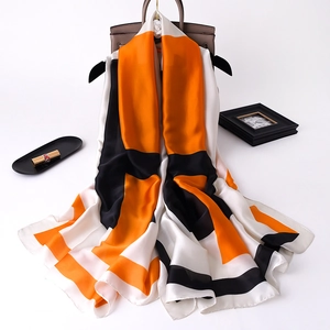 Close-up of geometric orange, black and white silk-feel scarf with smooth satin texture