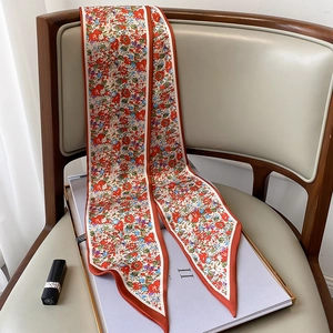 Detalle de pañuelo estrecho de seda con estampado floral y puntas afiladas en una silla